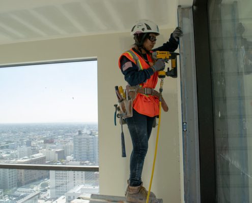 women construction hanging drywall